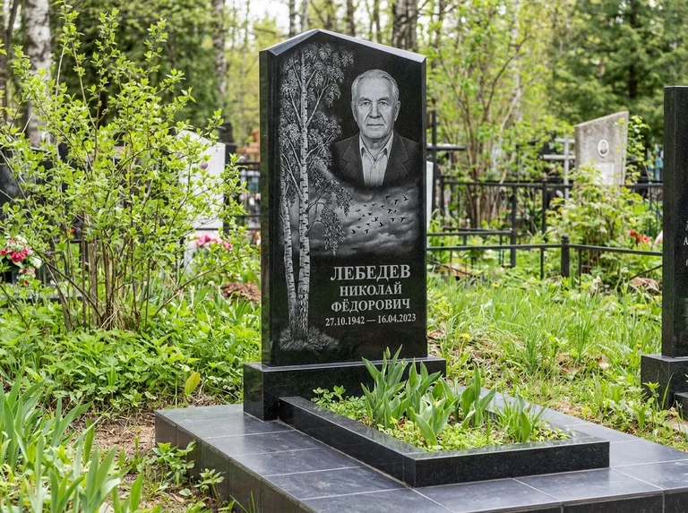 Памятник с гравировкой берёзы: вертикальная стела со скошенным верхом — берёза и стая птиц в небе, гранитный цоколь с тёмной плиткой, работа «Лебедев» в Альметьевске