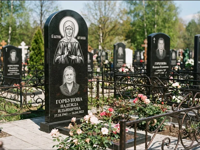 Памятник с гравировкой иконы: стела с арочным верхом и киотом под образ — гравировка образа Матроны Московской, гранитный цоколь с тёмной плиткой, работа «Ковалёв» в Альметьевске