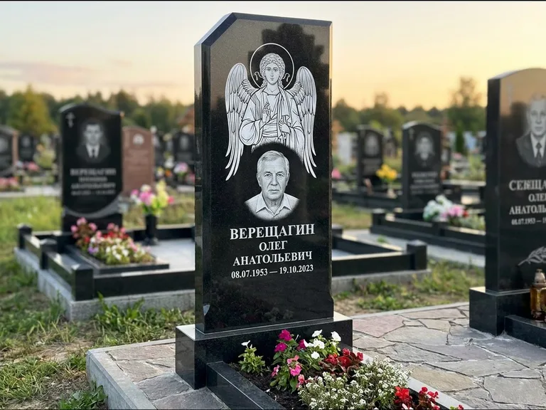 Памятник с гравировкой иконы: стела с резным навершием и нимбом в золоте — гравировка образа Спасителя, высокие разросшиеся туи полукругом, работа «Мельникова» в Альметьевске