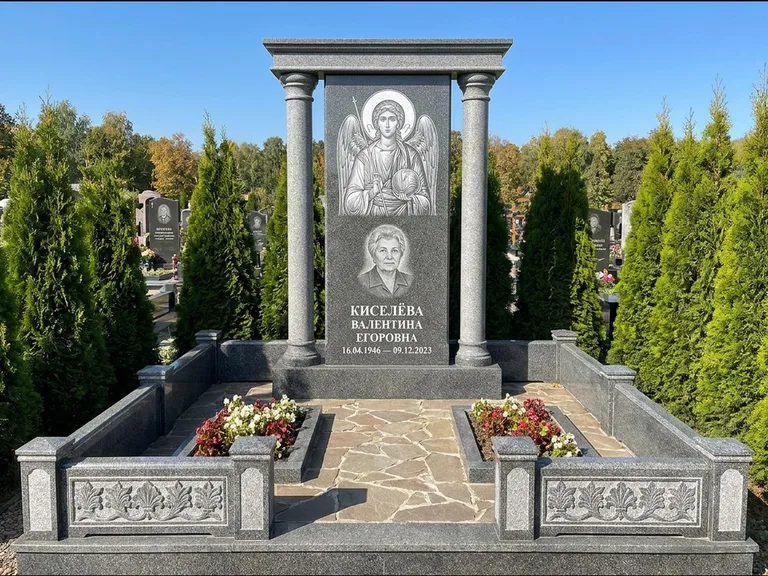 Памятник с гравировкой иконы: массивная стела с двускатным навершием-домиком — гравировка Николая Чудотворца, живая изгородь из туи, работа «Журавлёв» в Альметьевске