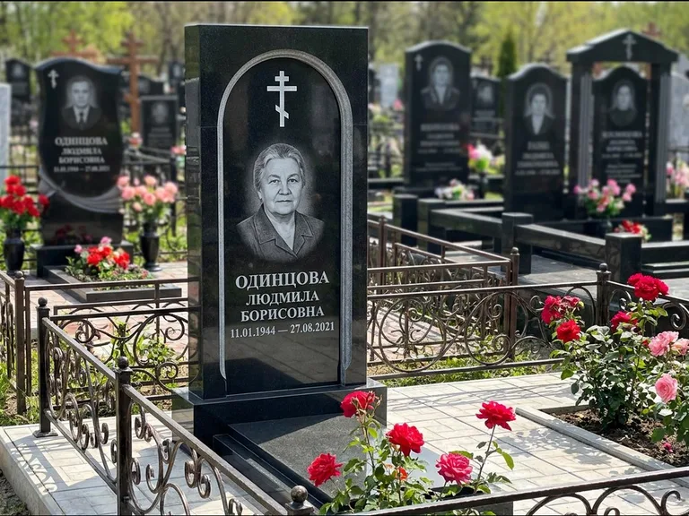 Памятник из чёрного гранита — скромная невысокая стела с крестом с терновым венцом, работа «Лаврентьева» в Альметьевске