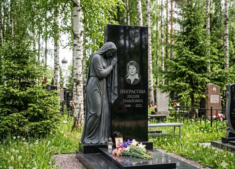 Гранитная фигура скорбящего мужчины у чёрной стелы в Альметьевске